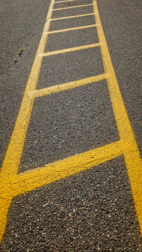 bright yellow pavement markings painted on an asphalt surface, resembling a ladder or a striped crosswalk. abstract concepts background