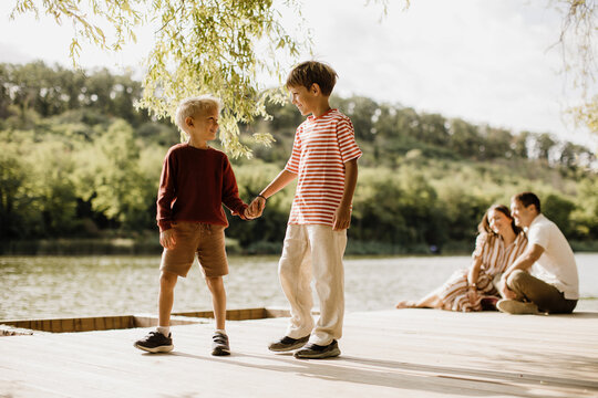Two young boys enjoy friendship at a peaceful lakeside in the afternoon sun