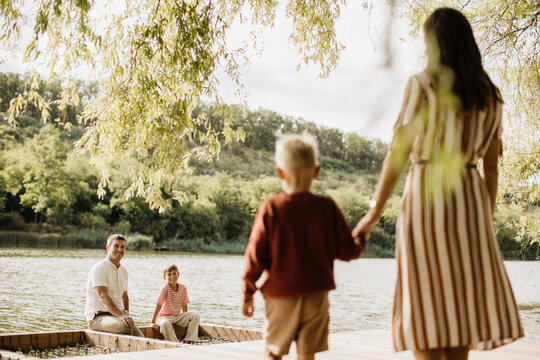 Family enjoying a sunny day by the serene lake with playful moments