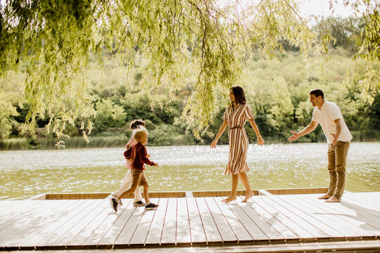 Family enjoying playful moments by the serene lakeside on a sunny day