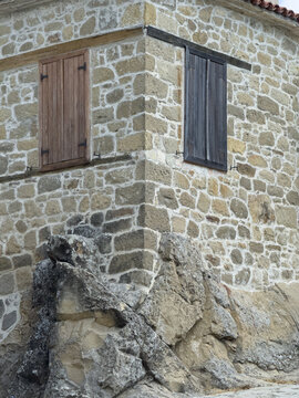 View of a historic stone building corner integrated into a natural rock foundation with wooden shutters in Canakkale, Canakkale, Turkiye.