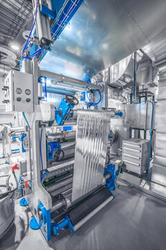 View of an industrial machine processing a reflective metallic foil in a modern manufacturing facility in Berlin, Berlin, Germany.