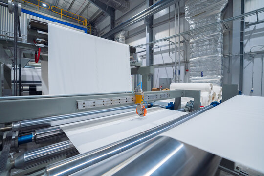 View of industrial paper manufacturing machine with rollers and white paper sheets in a factory in Berlin, Berlin, Germany.