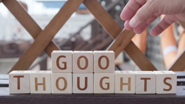 motivational word Good Thoughts, laying out  by hand from letters on wooden cubes, slow motion
