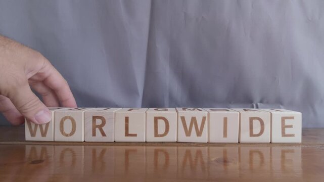 motivational word Worldwide, laying out by hand from letters on wooden cubes, slow motion

