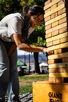 Woman leaning toward a giant wooden block stacking game