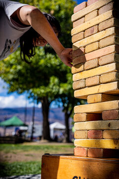 Close view of a woman pulling a block from a wooden tower