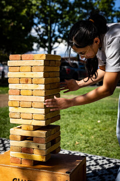 Woman carefully testing blocks in an outdoor wooden tower