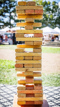 Precariously balanced wooden block tower at an outdoor event