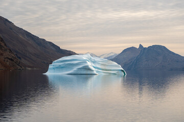 Iceberg in East Greenland floating at sunset in still water © Michael