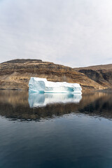 Iceberg in East Greenland floating at sunset in still water © Michael