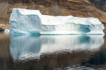 Iceberg in East Greenland floating at sunset in still water © Michael