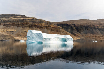 Iceberg in East Greenland floating at sunset in still water © Michael
