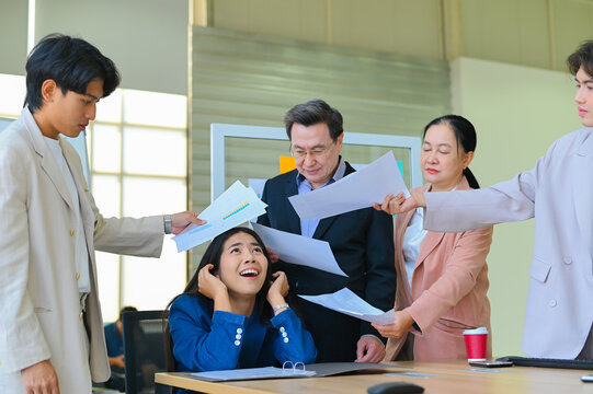 A tense moment in the office as an overwhelmed employee deals with multiple documents and coworkers demanding attention, highlighting workplace stress.