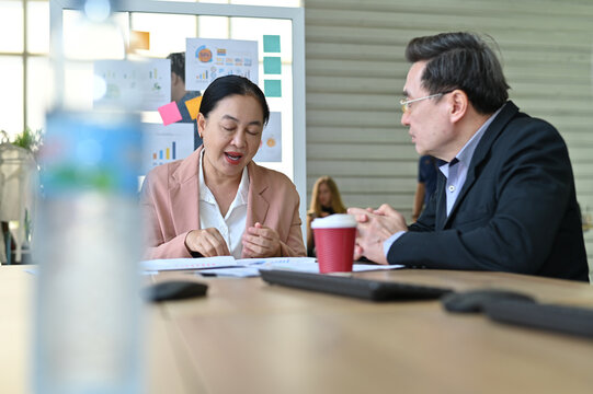 Two professionals engage in a deep discussion during a business meeting, sharing ideas and strategies for success in a modern office environment.