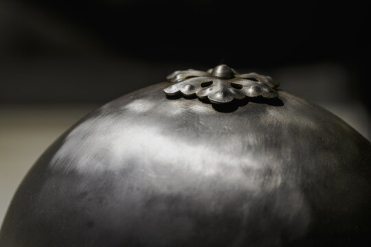 Detail of a metal flower on the top part of a metal helmet.