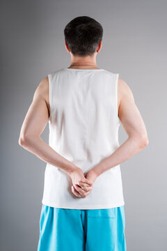 Unrecognizable man in sportswear performs exercises for muscles of upper back, arms and shoulder joint. Posture correction and physical therapy