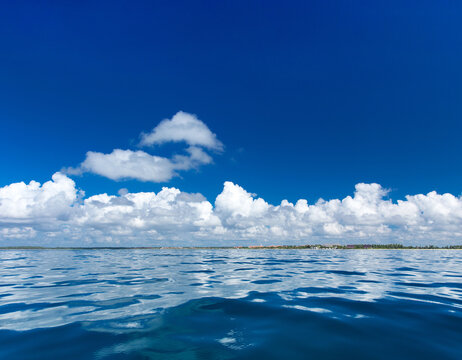 clouds on blue sky over calm sea with sunlight reflection