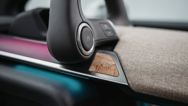 Detailed close up of a car steering wheel and dashboard with ambient lighting and cork trim