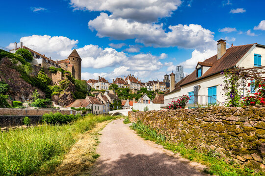 View of the historic medieval town of Semur-en-Auxois with stone towers, charming houses, and lush greenery under a bright blue sky in Semur-en-Auxois, Bourgogne-Franche-Comte, France.