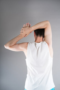 Unrecognizable man in sportswear performs exercises for muscles of upper back, arms and shoulder joint. Posture correction and physical therapy