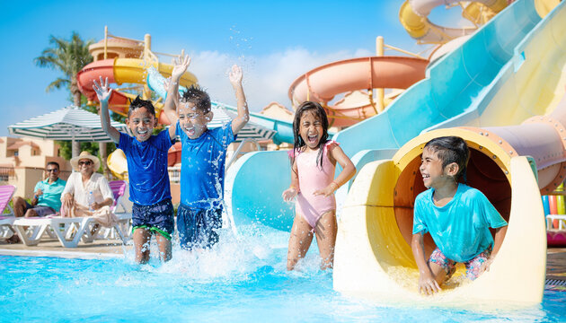 Children playing and sliding in a water park with water slides.