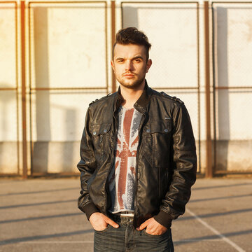 Spring portrait of a young guy in a leather jacket on a sunny day.