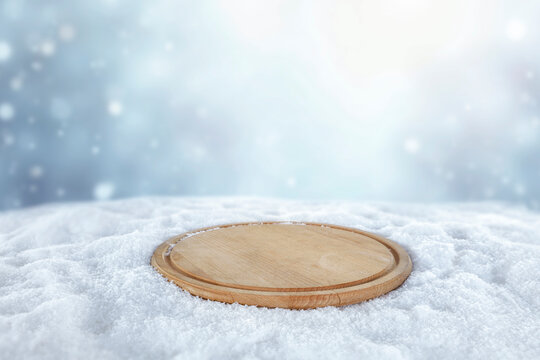 Empty wooden board with copy space in snowy winter landscape &ndash; seasonal product concept.