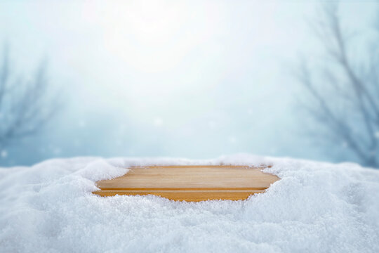 Empty wooden board with copy space in snowy winter landscape &ndash; seasonal product concept.