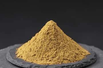 Obraz premium dried basil leaves powder from the plant ocimum basilicum on a black slate stone tray