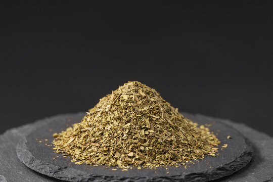 Mentha piperita or mint leaves flakes on a black slate stone tray