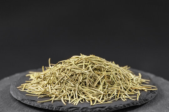 dried rosemary leaves on a black slate stone tray