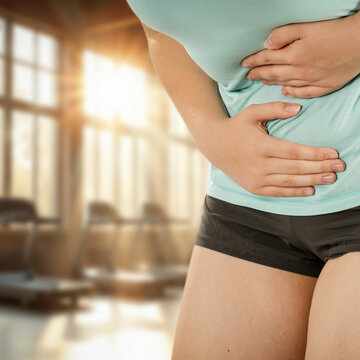Woman stretching and massaging painful body areas of stomach&ndash; muscle pain and health concept.