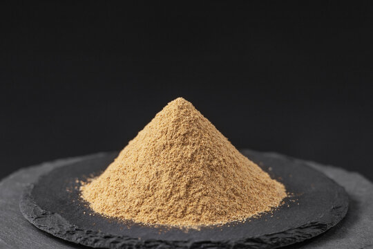 green cardamom powder pods on a black slate stone tray