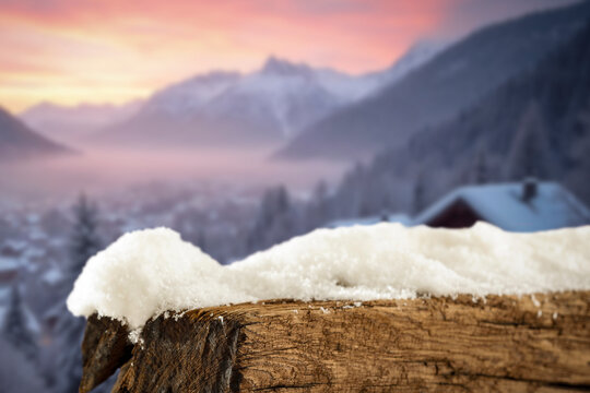 Empty covered with snow tree trunk for product placement, surrounded by fresh snow and a beautiful winter landscape in the background.