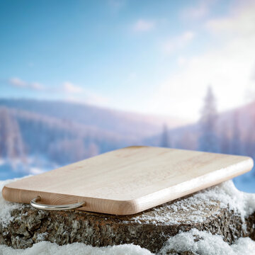 Empty covered with snow tree trunk for product placement, surrounded by fresh snow and a beautiful winter landscape in the background.