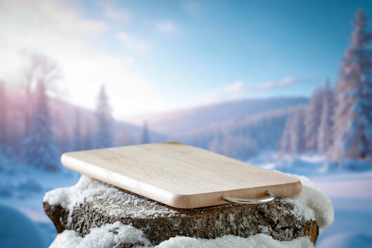 Empty covered with snow tree trunk for product placement, surrounded by fresh snow and a beautiful winter landscape in the background.