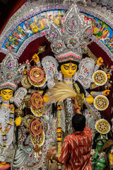 Fototapeta premium Traditional Bengali Durga Puja Idol with hindu priest performing aarti rituals to Goddess Durga during religious festival.