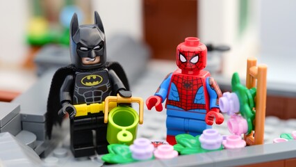 Fototapeta premium Tambov, Russian Federation - August 23, 2026 Lego Batman and Spider-Man minifigures gardening together on a rooftop terrace.