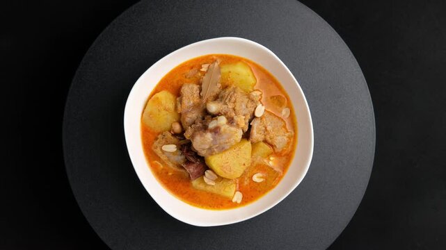Massaman Curry with baby pork ribs (pork cartilage).Cooked pork meat and potatoes groundnut with massaman curry paste in coconut milk on white bowl.asian food.Top view.	