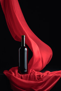 Bottle of red wine and flutters of red cloth.