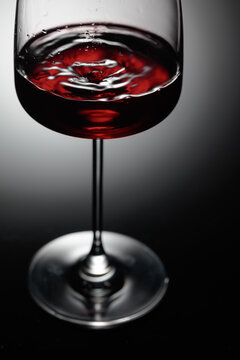 The drop of red wine falls into a wine glass.