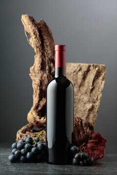 Bottle of red wine with stone, dried snags, and blue grapes.