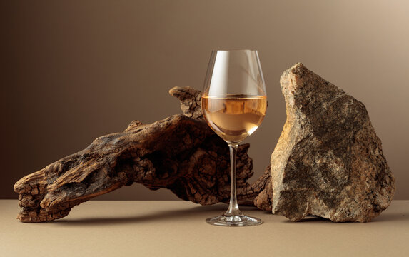 Glass of white wine with old driftwood and a piece of granite rock.