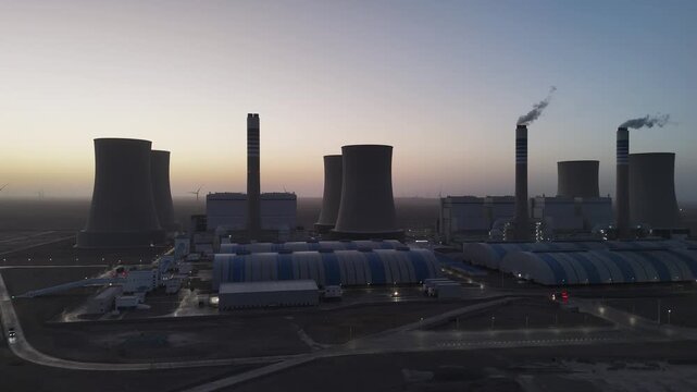 Large thermal power plant panorama at dusk with cooling towers and smoke stacks
