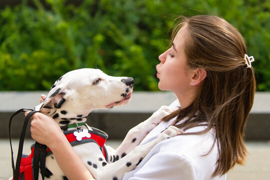 Dog giving affectionate lick to woman. Dog looking at owner's face. Woman sharing kiss with dog outdoors. Pet love between dog and human.