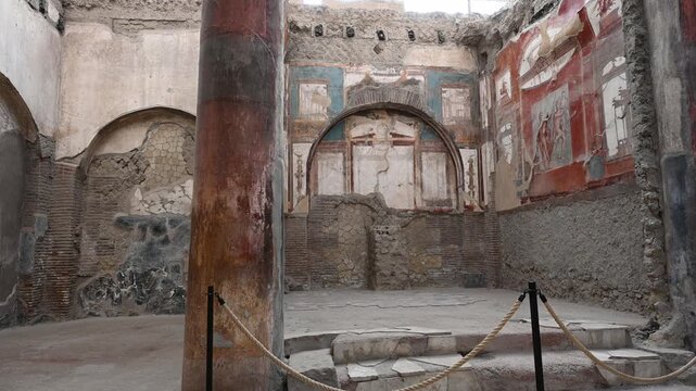 ERCOLANO, ITALY - SEPTEMBER 20, 2026: Ancient Roman frescoes in Pompeian red inside the College of Augustales (Sede degli Augustali) in the archaeological site of Herculaneum.