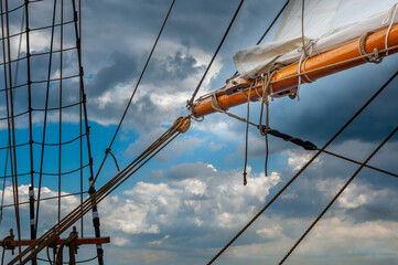 Wooden gaff and furled sail against cloudy sky © Georg