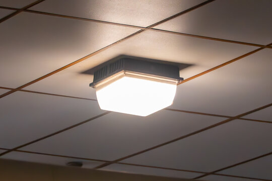 Bright illuminated ceiling light fixture on a grid false ceiling, providing modern interior lighting in an office or commercial building, clean design and energy efficient glow.