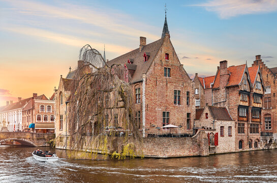 Bruges, Belgium. Ancient medieval architecture of brugges. Old stone and wooden houses above water channels with travel boat in Brugge. Sunset in Historic town, famous european landmark.